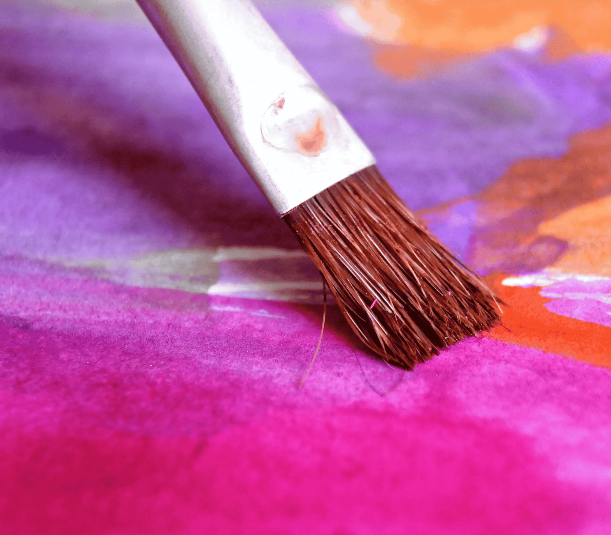 Paint brush creating vibrant purple and orange watercolor blend